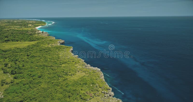 Aerial view of blue ocean bay at green tropic landscape. Greenery grass valley at cliff sea shore