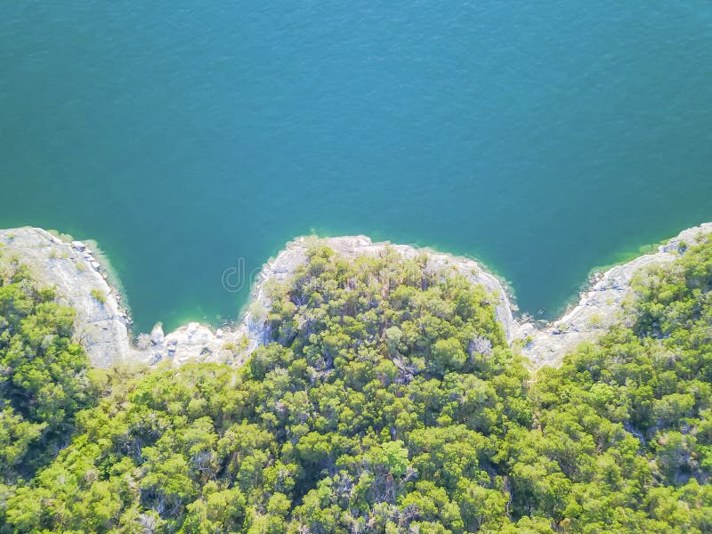 Aerial trees and cliff rock wall crystal water at Lake Travis, A