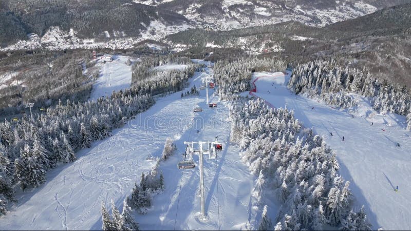 Aerial view of chairlift with skiers and snowboarders on snowy mountain slope. stock footage