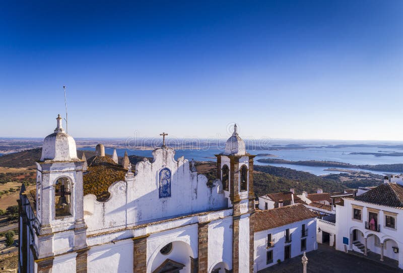 Aerial view of a church facade in the historic village of Monsaraz in Alentejo with the Alqueva dam reservoir on the background