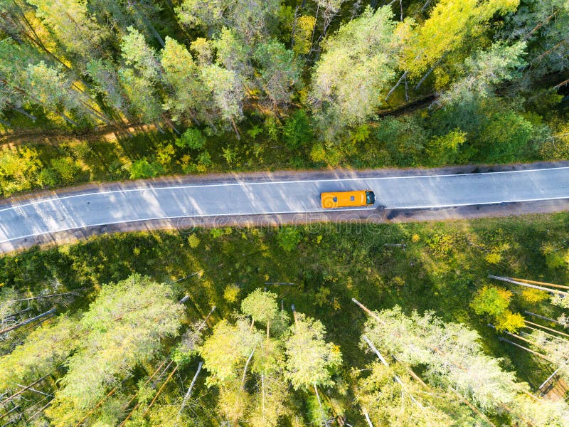 Aerial view of a country road in the forest with moving cars. Beautiful landscape. Captured from above with a drone. Aerial bird`