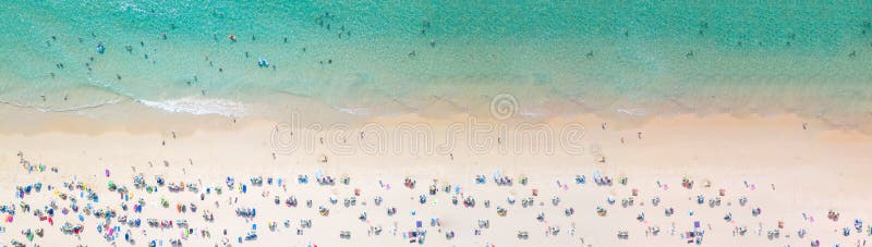 Aerial view crowded public beach with colourful umbrellas, Aerial view of sandy beach with tourists swimming in beautiful clear sea waterà¹ƒ