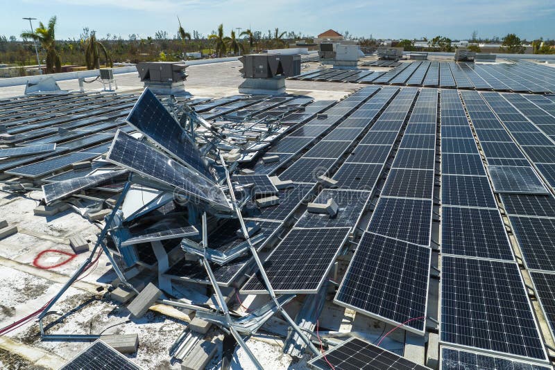 Aerial view of damaged by hurricane wind photovoltaic solar panels mounted on industrial building roof for producing