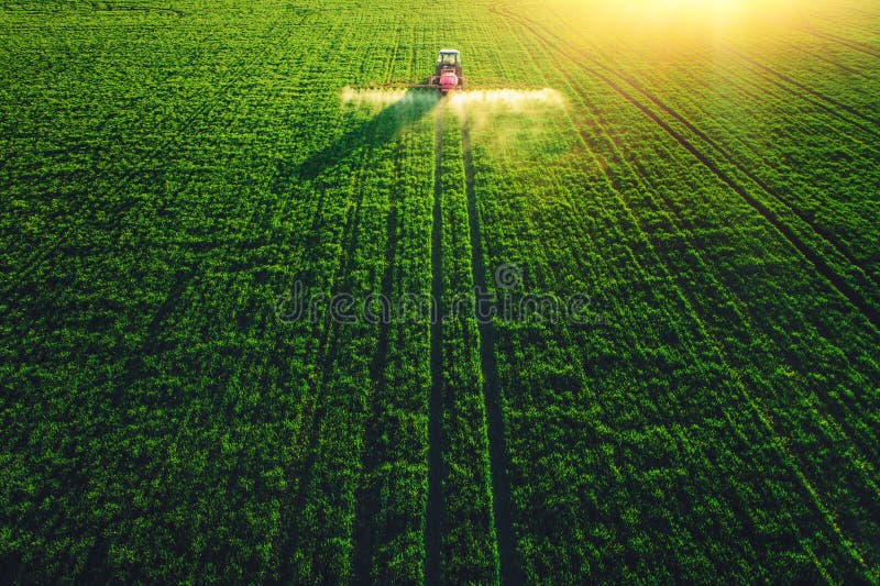 Aerial view of farming tractor plowing and spraying on field