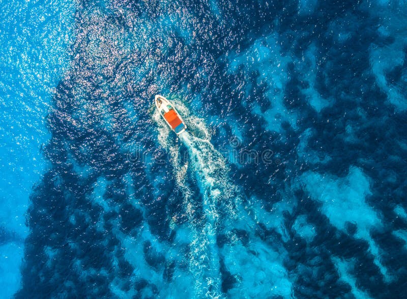 Aerial view of floating speed boat in transparent blue water