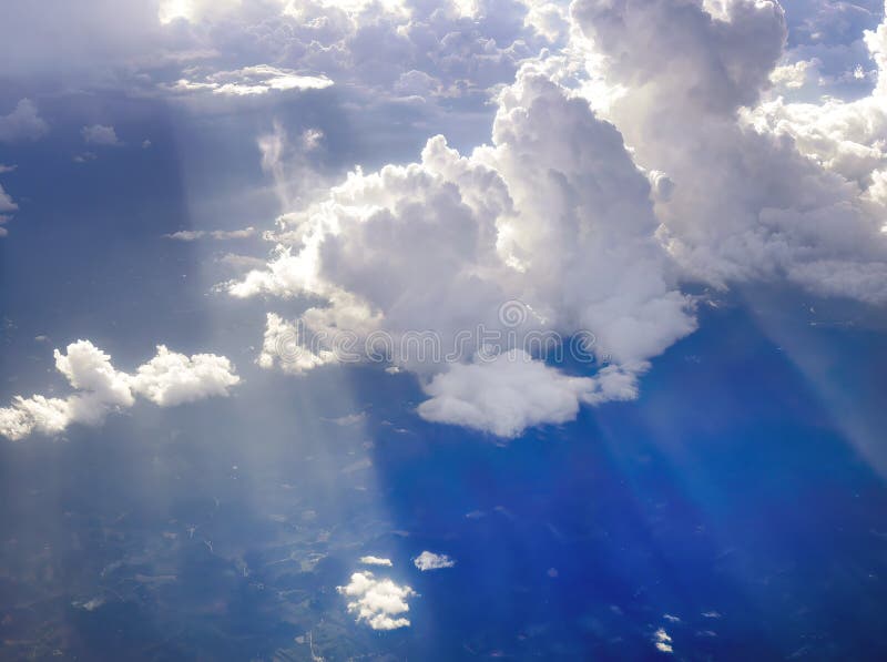 Aerial view flying above dramatic fluffy clouds and sun rays piercing shining through the clouds, cloudscape, sunlight stock photography