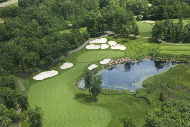 Aerial view of golf fairway and green with traps, pond and trees stock photo