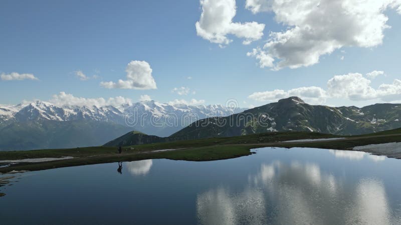 Aerial view of hiker with backpack walking by Koruldi lakes in Svaneti mountains. Man hiking near tranquil water stock footage