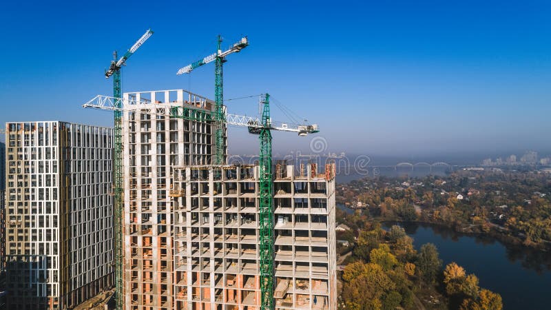 Aerial view of landscape in the city with under construction buildings and industrial cranes. Construction site.