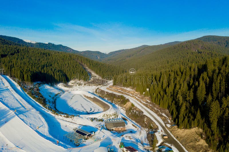 Aerial view of landscape of ski and snowboard slopes through pine trees going down to winter resort in Carpathians. stock photo Aerial view of landscape of ski and snowboard slopes through pine trees going down to winter resort in Carpathians. stock photo