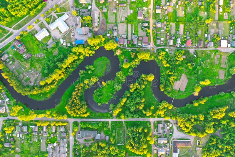 Aerial view landscape of winding small river among the small town, stream in green field