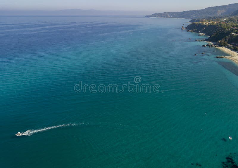 Aerial view of a motor boat sailing near the rocks and the beach