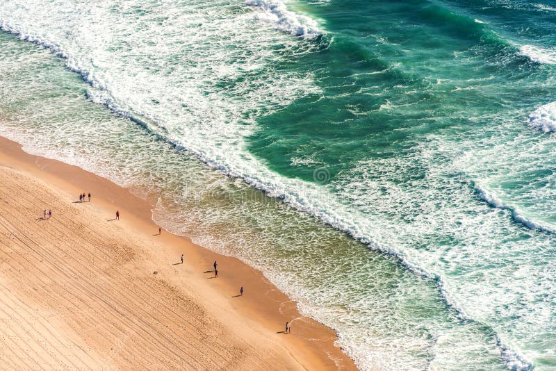 Aerial view of ocean beach. Aerial view from above of ocean, sea beach and water waves with people on sand shore with emphasis of the scale of people and nature stock image Aerial view of ocean beach. Aerial view from above of ocean, sea beach and water waves with people on sand shore with emphasis of the scale of people and nature stock image
