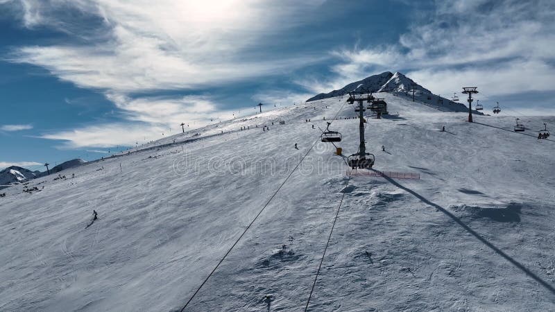 Aerial view over snowy mountain winter forest with chair lift at ski resort. stock video footage