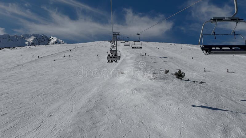 Aerial view over snowy mountain winter forest with chair lift at ski resort. stock video