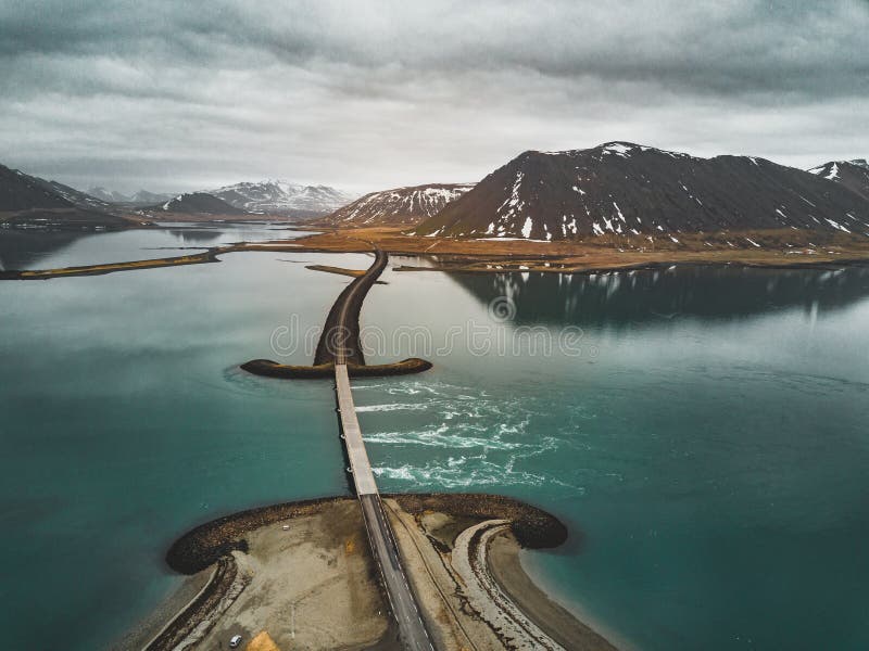 Aerial view of road 1 in iceland with bridge over the sea in Snaefellsnes peninsula with clouds, water and mountain in