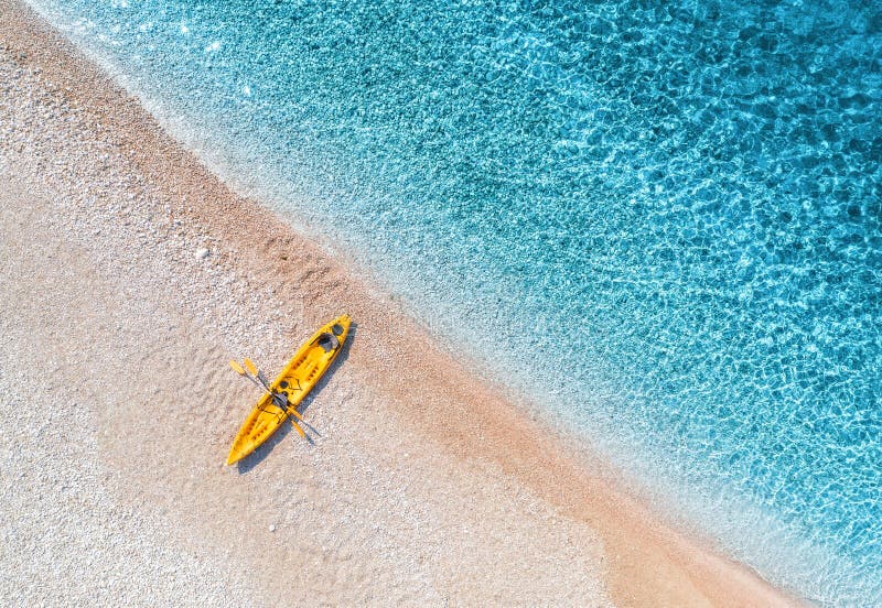 Aerial view of sandy beach with yellow canoe and blue sea