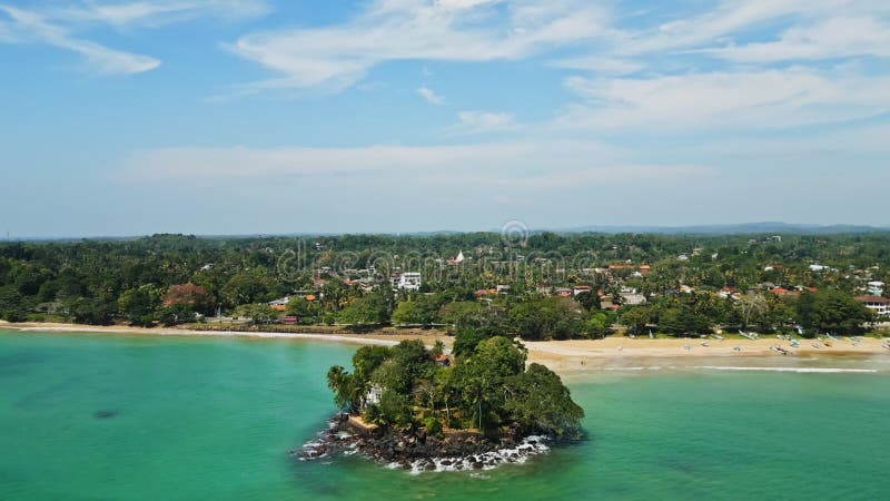 Aerial view of secluded island, solitary house amidst lush greenery by tranquil turquoise lagoon, sandy beach nearby