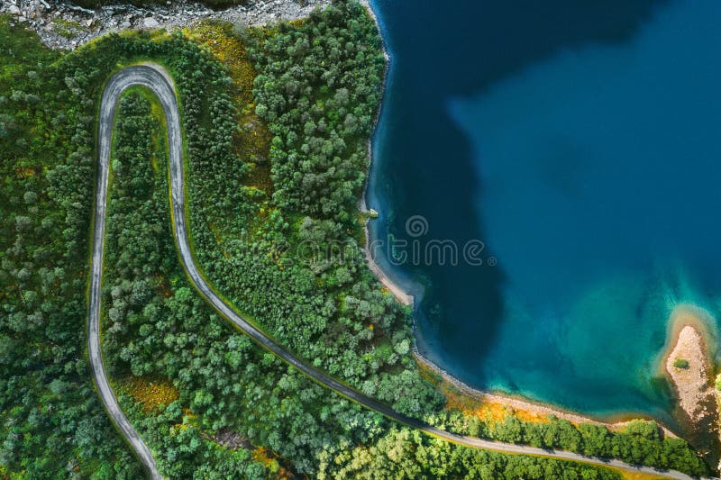 Aerial view serpentine road and forest with sea drone landscape in Norway. Above trees and blue sea water scandinavian nature wilderness top down scenery stock image Aerial view serpentine road and forest with sea drone landscape in Norway. Above trees and blue sea water scandinavian nature wilderness top down scenery stock image