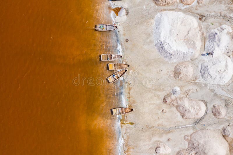 Aerial view of the small boats for salt collecting at pink Lake Retba or Lac Rose in Senegal. Photo made by drone from above.