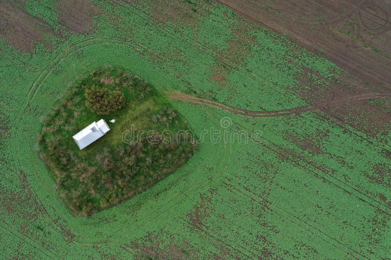 Aerial view of small white chapel in the middle of agricultural field stock photography
