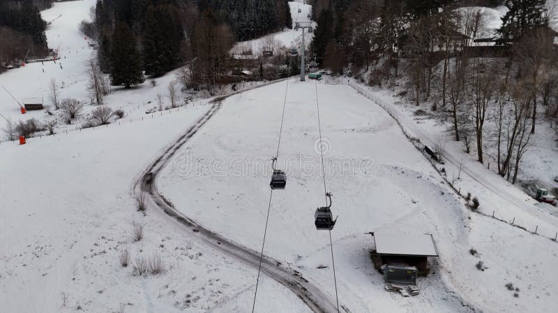 Aerial view of snowy mountain road with a ski lift in the background. stock video footage