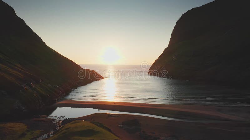 Aerial view of sunset on the beach with awesome sun golden reflection on calm waves. Golden beach and mountain