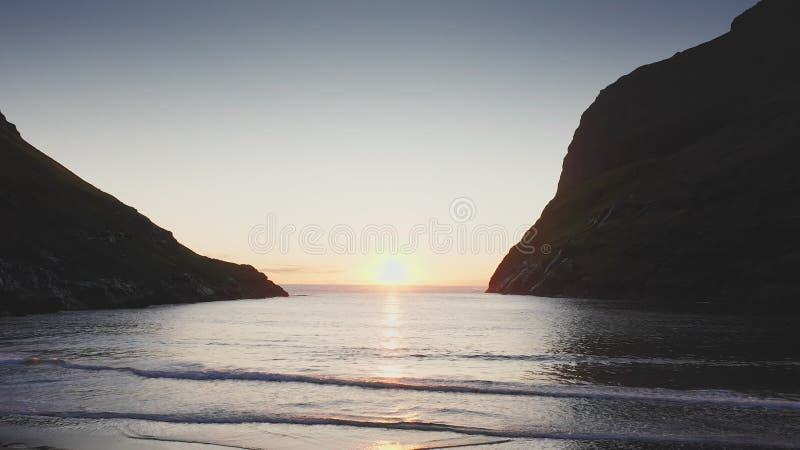 Aerial view of sunset on the beach with awesome sun golden reflection on calm waves. Golden beach and mountain