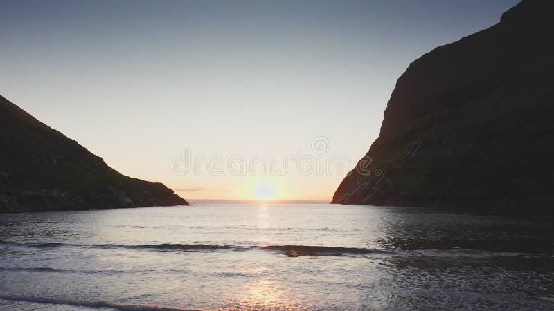 Aerial view of sunset on the beach with awesome sun golden reflection on calm waves. Golden beach and mountain