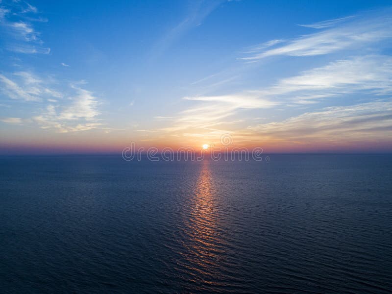 Aerial view of a Sunset sky background. Aerial Dramatic gold sunset sky with evening sky clouds over the sea. Stunning sky clouds