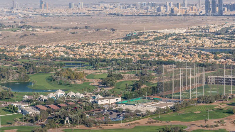 Aerial view to Golf course green lawn and lakes, villa houses behind it timelapse. Village triangle and circle district. Top view from Dubai marina skyscraper. Aerial view to Golf course green lawn and lakes, villa houses behind it timelapse. Village triangle and circle district. Top view from Dubai marina skyscraper.