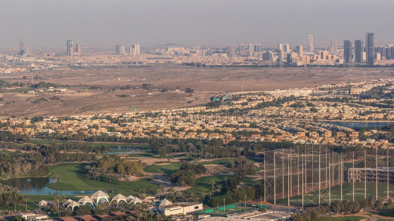 Aerial view to Golf course green lawn and lakes, villa houses behind it timelapse. Village triangle and circle district. Top view from Dubai marina skyscraper. Aerial view to Golf course green lawn and lakes, villa houses behind it timelapse. Village triangle and circle district. Top view from Dubai marina skyscraper.