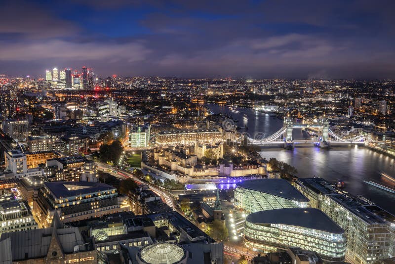 Aerial view to the illuminated skyline of London, UK, during night time featuring the famous Tower Bridge and the modern office buildings around