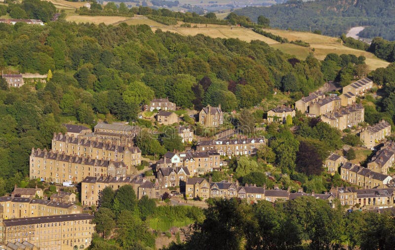 Aerial view of the town of hebden bridge in summer with hillside sloping streets of stone house surrounded by green woodland an