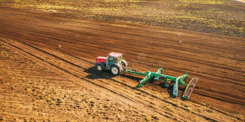 Aerial View. Tractor Plowing Field. Beginning Of Agricultural Spring Season. Cultivator Pulled By A Tractor In