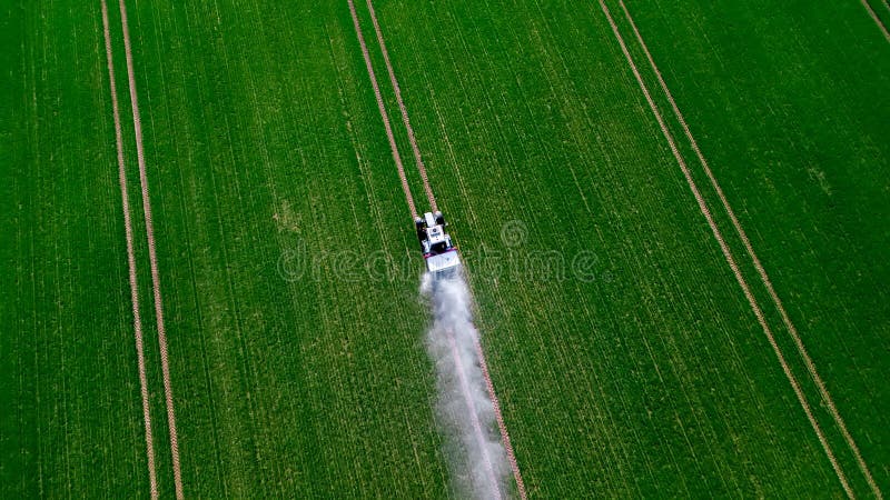 Aerial view of the tractor spraying the chemicals on the large green field stock photos Aerial view of the tractor spraying the chemicals on the large green field stock photos