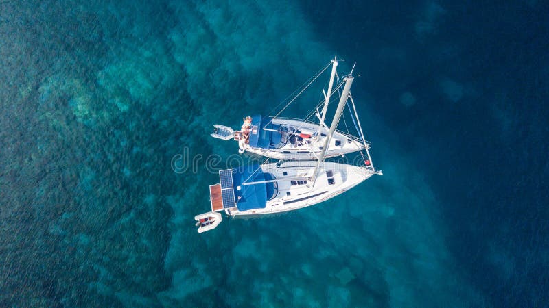 Aerial view of two anchoring yacht in open water.