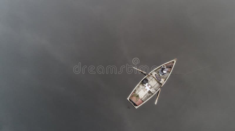 Aerial view about a very simple fishing boat on a cold autumn foggy morning near a beautiful fishing lake in Sic. Romania