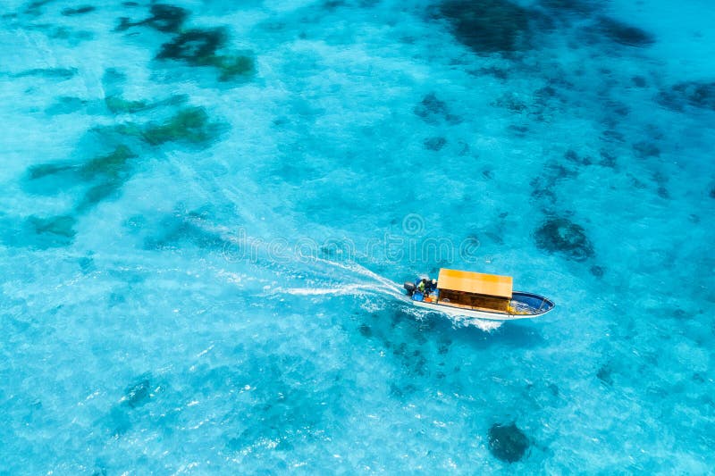 Aerial view of the white boat in the clear blue water at sunset