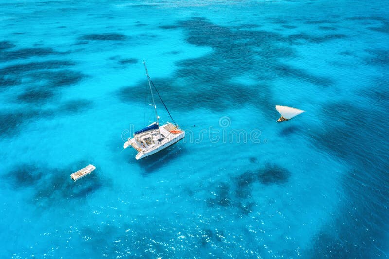 Aerial view of the yacht and sailboat in clear blue sea at sunset