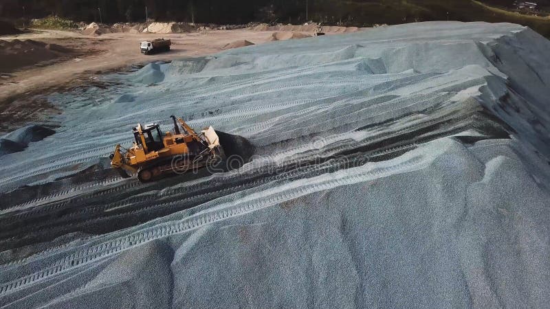 Aerial view of yellow excavator or bulldozer works in sand quarry at the construction site. Stock footage. Industrial