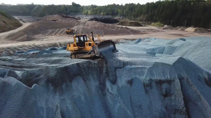 Aerial view of yellow excavator or bulldozer works in sand quarry at the construction site. Stock footage. Industrial