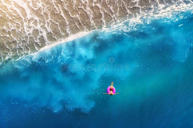 Vista aerea da giovane donna nuoto sul rosa nuotare squillo trasparente turchese il mare,.