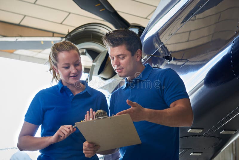 Aero Ingenieur And Apprentice Working auf Hubschrauber im Hangar lizenzfreie stockfotografie Aero Ingenieur And Apprentice Working auf Hubschrauber im Hangar lizenzfreie stockfotografie