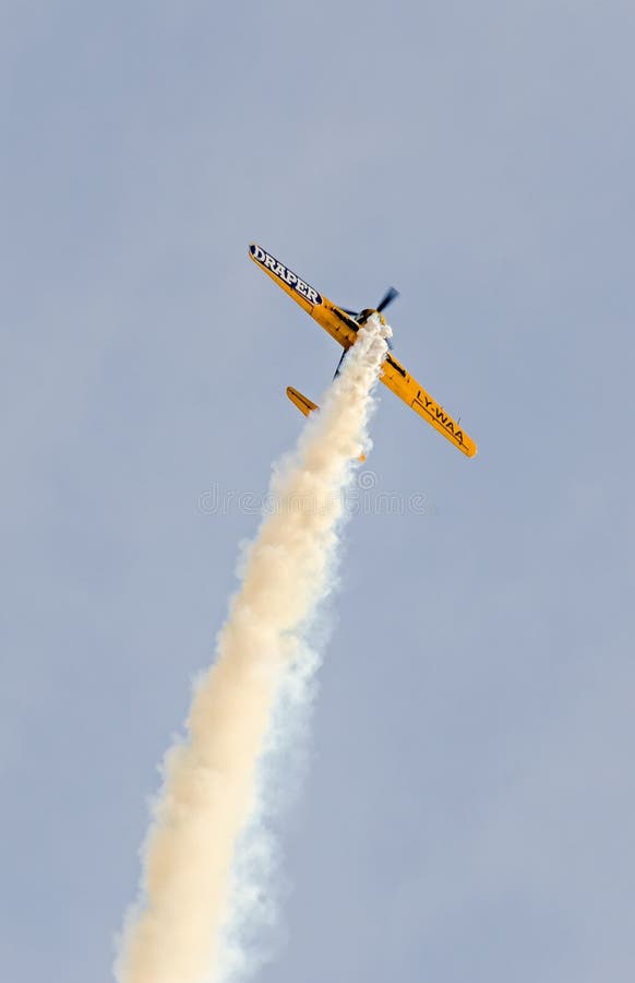 Aerobatic airplane pilot Jurgis Kairys training in the sky of the city. Colored airplane with trace smoke, airbandits, aeroshow