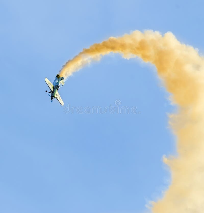 Aerobatic airplane pilot Jurgis Kairys training in the sky of the city. Colored airplane with trace smoke, airbandits, aeroshow