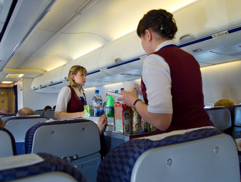 Aeromoços que servem o alimento aos passageiros durante o voo foto de stock Aeromoços que servem o alimento aos passageiros durante o voo foto de stock