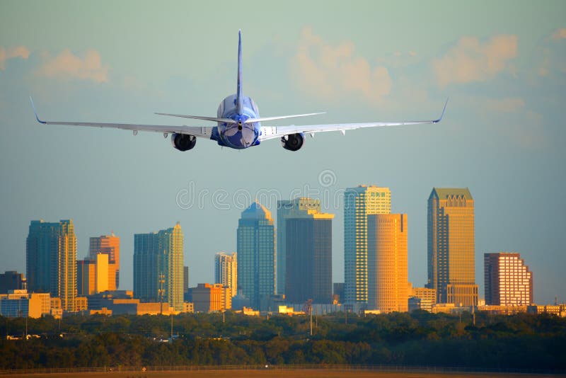 Tampa, Florida, skyline with warm sunset light with a commercial passenger jet airliner plane arriving or departing the International Airport. Tampa, Florida, skyline with warm sunset light with a commercial passenger jet airliner plane arriving or departing the International Airport.