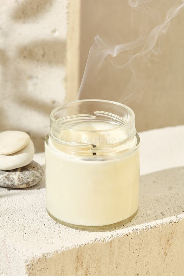 Aesthetic composition with aromatic candle in jar and smoke. Mockup soy wax candle in natural style with stone. Scented handmade