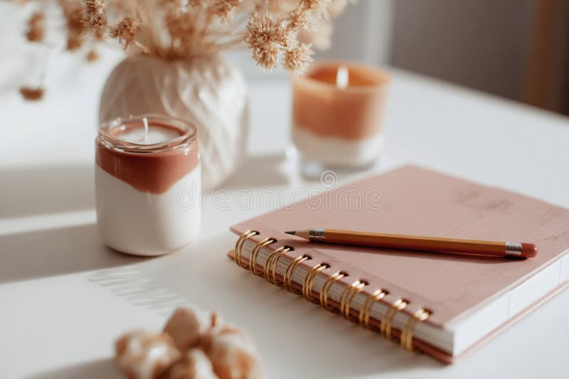 Aesthetic desk setup featuring pink spiral planner, pencil, and candles stock photography